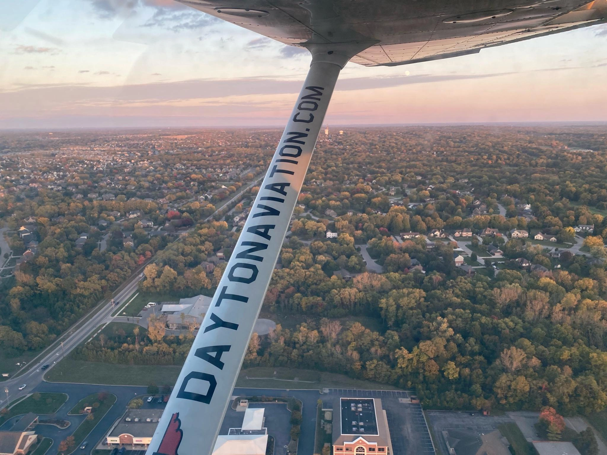 Airplane wing over the city at dusk during a Dayton Aviation Services flight